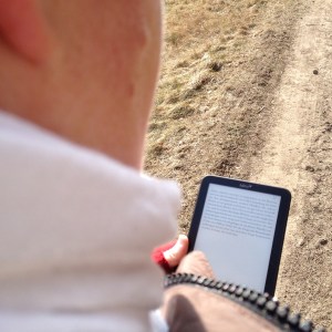 Kerstin Cornils auf einem Spaziergang durch den Wald. Sie hält einen Tolino Shine in der Hand und liest "Das Original" von John Grisham