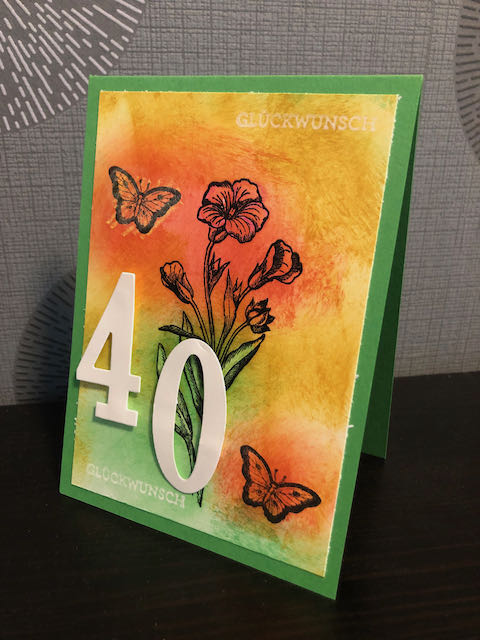 Gebastelte Karte zum 40. Geburtstag. Die Grundkarte ist grün, dadrauf ist ein buntes Papier mit einer gestempelten Blume und zwei Schmetterlingen. Erhaben sind die Ziffern 4 und 0 auf die Karte geklebt. 