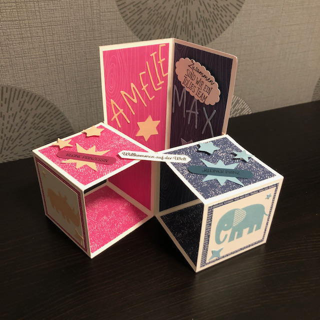 Triple Pop Up Cube Card für Zwillinge. Die Karte ist in Pink und Blau gebastelt. Die Seite für Amelie ist pink mit Sternen und einem Nashorn und die Seite für Max ist blau mit Sternen und einem Elefanten. 