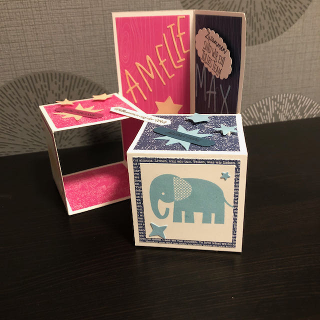 Triple Pop Up Cube Card für Zwillinge. Die Karte ist in Pink und Blau gebastelt. Die Seite für Amelie ist pink mit Sternen und einem Nashorn und die Seite für Max ist blau mit Sternen und einem Elefanten. 