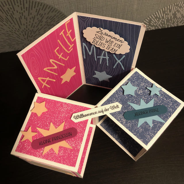 Triple Pop Up Cube Card für Zwillinge. Die Karte ist in Pink und Blau gebastelt. Die Seite für Amelie ist pink mit Sternen und einem Nashorn und die Seite für Max ist blau mit Sternen und einem Elefanten. 