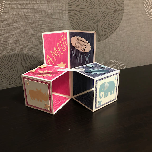 Triple Pop Up Cube Card für Zwillinge. Die Karte ist in Pink und Blau gebastelt. Die Seite für Amelie ist pink mit Sternen und einem Nashorn und die Seite für Max ist blau mit Sternen und einem Elefanten. 