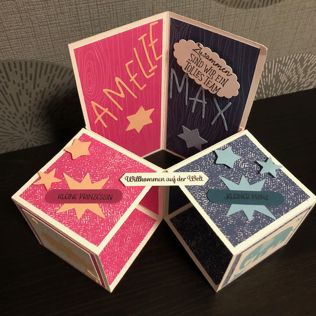 Triple Pop Up Cube Card für Zwillinge. Die Karte ist in Pink und Blau gebastelt. Die Seite für Amelie ist pink mit Sternen und einem Nashorn und die Seite für Max ist blau mit Sternen und einem Elefanten. 
