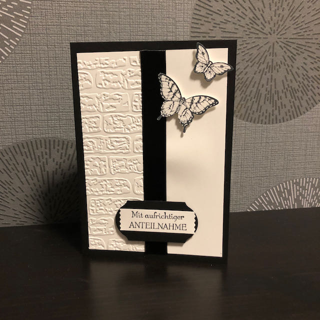 gebastelte Trauerkarte mit geprägter Mauer, schwarzem Band und zwei Schmetterlingen die Richtung Himmel fliegen. Als Spruch: Mit aufrichtiger Anteilnahme