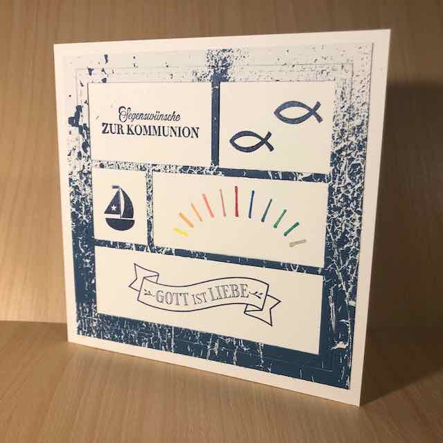 Eine Karte zur heiligen Erstkommunion. Darauf gestempelt sind unter anderem zwei Fische, ein Segelboot, ein Banner mit den Worten: Gott ist Liebe und ein Regenbogen. Die Karte ist quadratisch und mit Produkten von Stampin Up gebastelt.