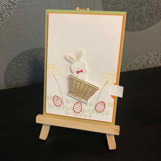 Wackelkarte zu Ostern. Durch ziehen am Papierstreifen bewegt sich der Osterhase im Körbchen von rechts nach links und wieder zurück.