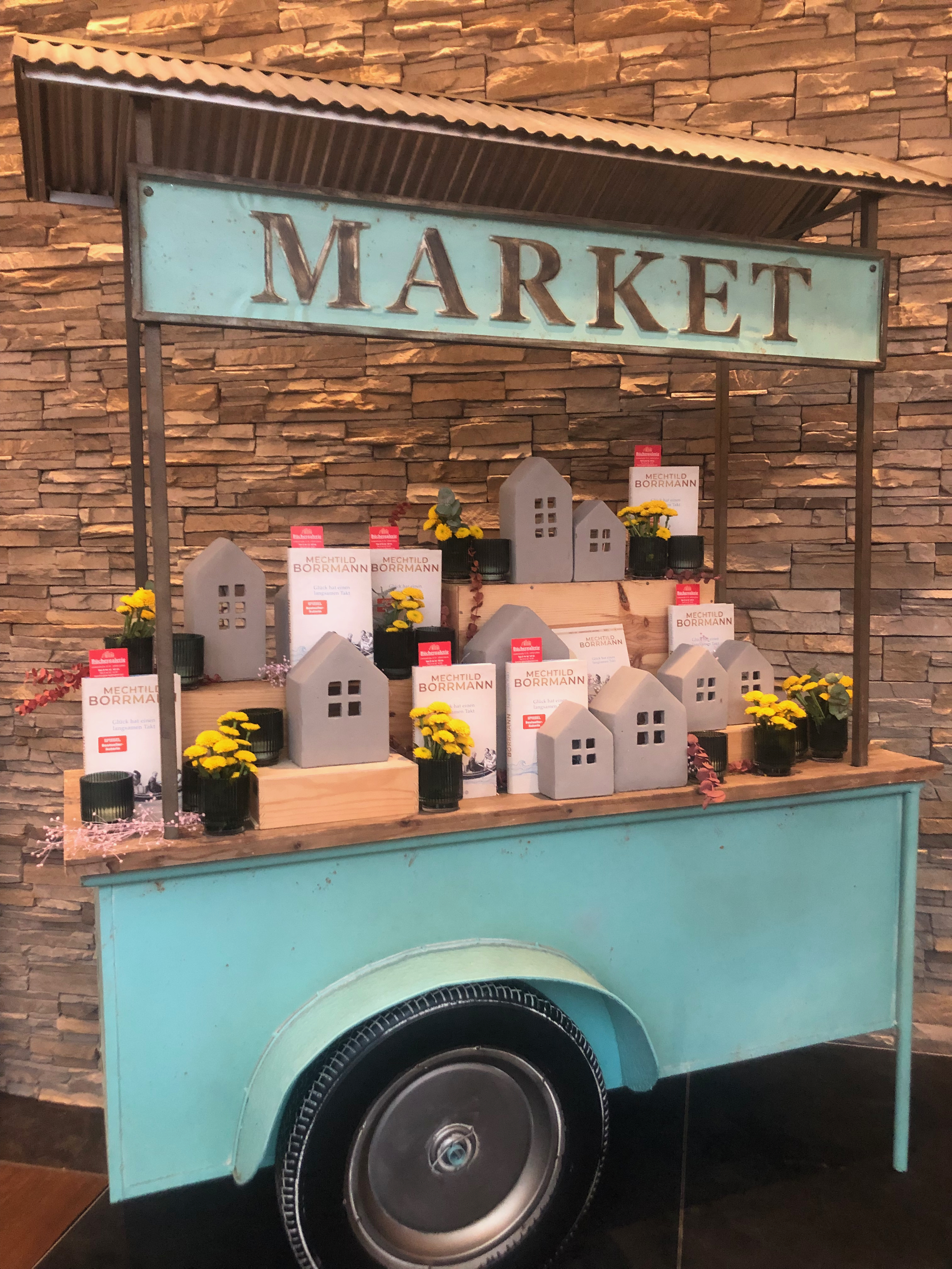 Bücherwagen zur Lesung von Mechtild Borrmann. Auf dem Wagen stehen mehrer Bücher: Glück hat einen langsamen Takt.