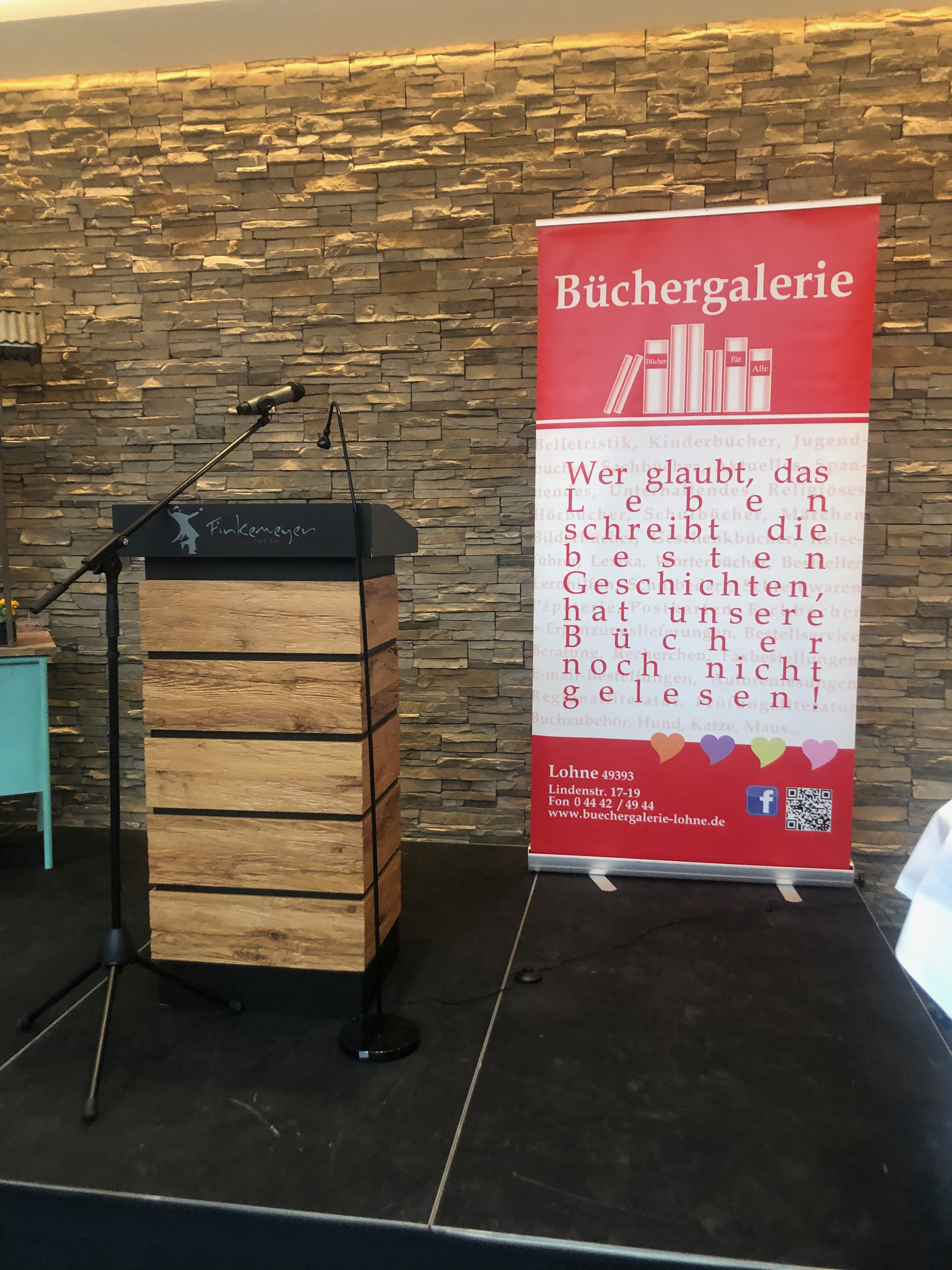 Lesepult und Banner der Büchergalerie Lohne zur Lesung von Mechtild Borrmann aus ihrem Buch: Glück hat einen langsamen Takt.