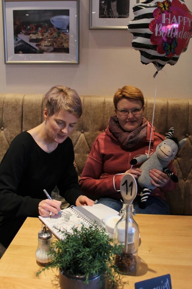 Ein Foto von der Kinderbuch Autorin Stephanie Schneider und mir mit dem Zesel Möhrchen, während sie meine Sketchnotes zum Buch: Grimm und Möhrchen - Ein Zesel zieht ein für mich signiert