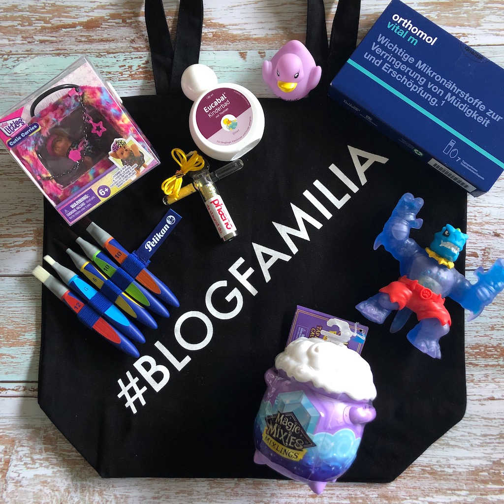 Inhalt der Goodie Bag der Blogfamilia 2022. Der Inhalt stammt von folgenden Sponsoren: Phaeno Wolfsburg, Arena Verlag, Beltz Verlag, Moose Toys, Orthomol, Pelikan, Eucabal, Symplr.together, Migo Verlag, Eule findet den Beat, Fischer Kinder- und Jugendbuch, Volovo, Amrit.