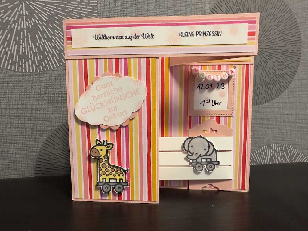 Z Fold Babykarte in rosa für ein Mädchen. Die Karte steht von alleine durch das Babybett, dass sich ausklappen lässt. Der Name hängt in einer Perlenkette über dem Bett.