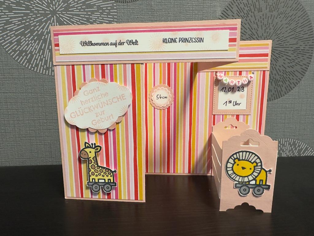 Z Fold Babykarte in rosa für ein Mädchen. Die Karte steht von alleine durch das Babybett, dass sich ausklappen lässt. Der Name hängt in einer Perlenkette über dem Bett.