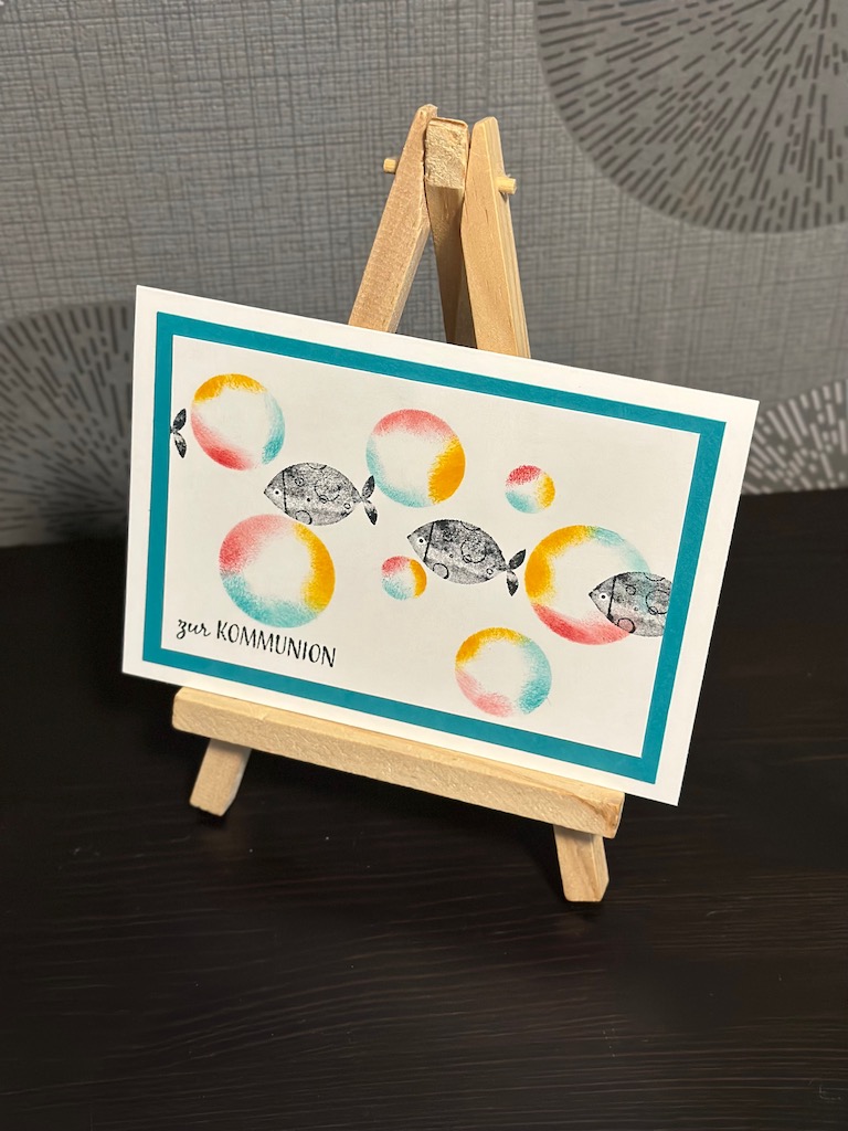 Glückwunschkarte zur Kommunion mit farbigen Seifenblasen und einem Schwarm Fische, die scheinbar hindurch schwimmen