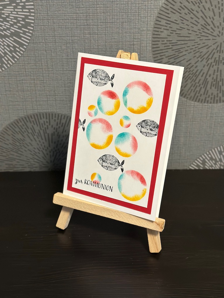 Glückwunschkarte zur Kommunion mit farbigen Seifenblasen und einem Schwarm Fische, die scheinbar hindurch schwimmen