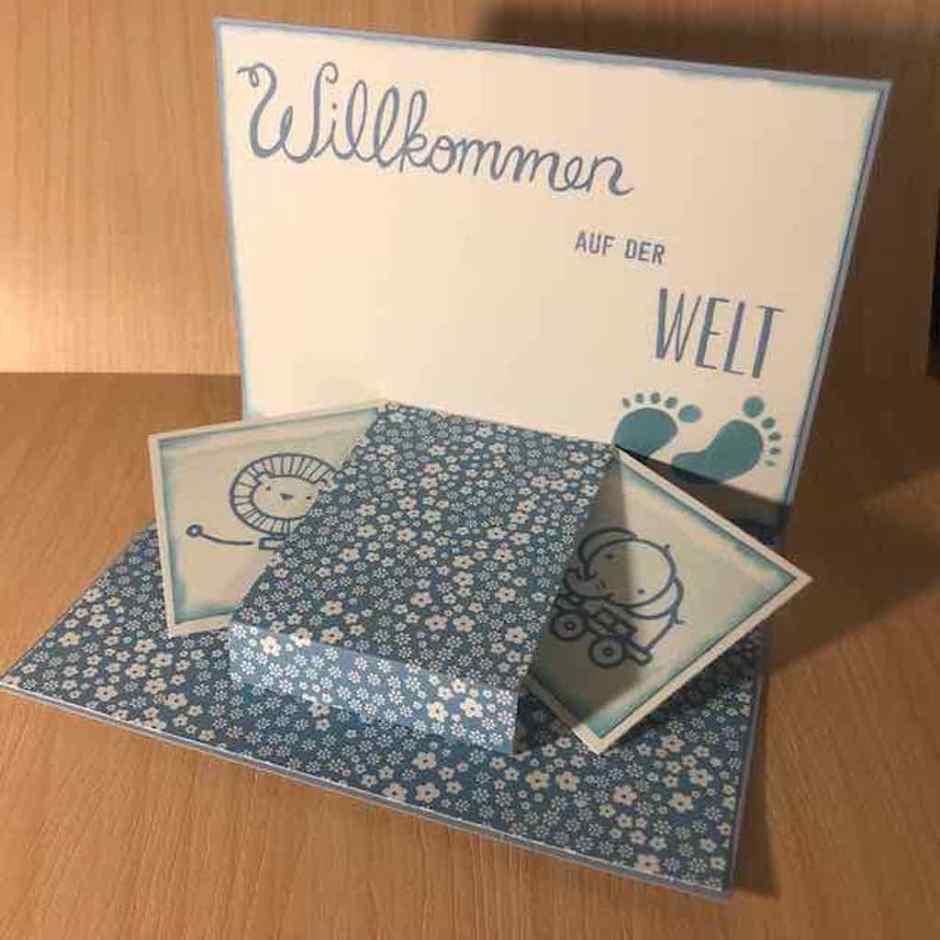 Babykarte selbstgemacht in verschiedenen Blautönen kombiniert mit weiß. Die Karte hat im Inneren ein Pop-up-Element. Es kommen ein kleiner Löwe und ein kleiner Elefant zum Vorschein.