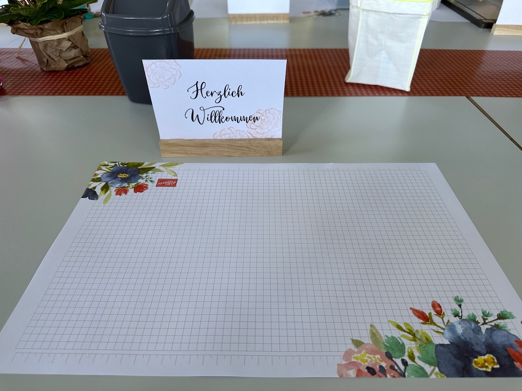 Mein Arbeitsplatz beim Teamtreffen vom Team Stempelspass in Jever in der Jugendherberge. Zu sehen ist die Arbeitsunterlage und ein Schild mit Herzlich Willkommen