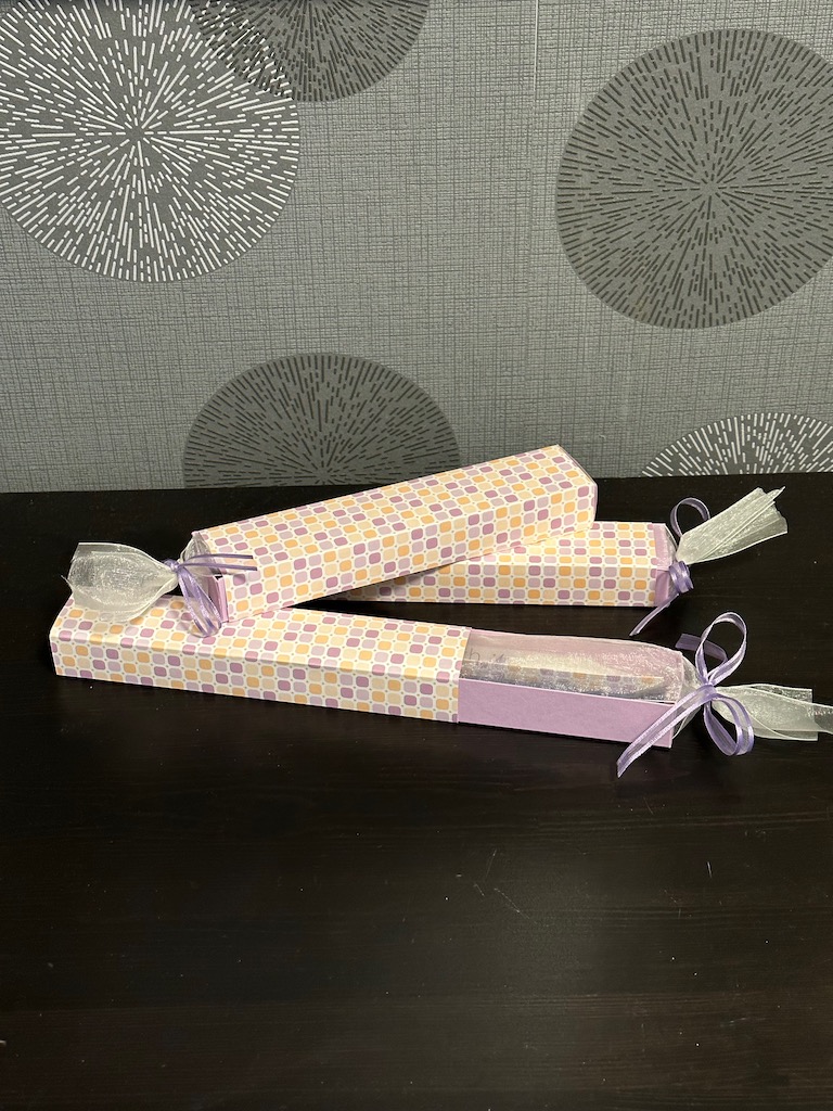 Längliche Box mit einer Kerze und etwas Schokolade als MItbringsel