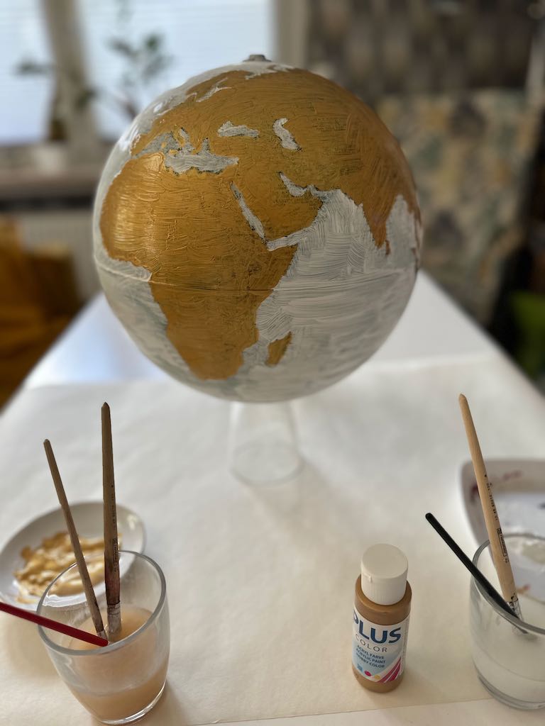 Globus bzw. Weltkugel in weiß und gold angemalt dient als Gästebuch für eine Hochzeit