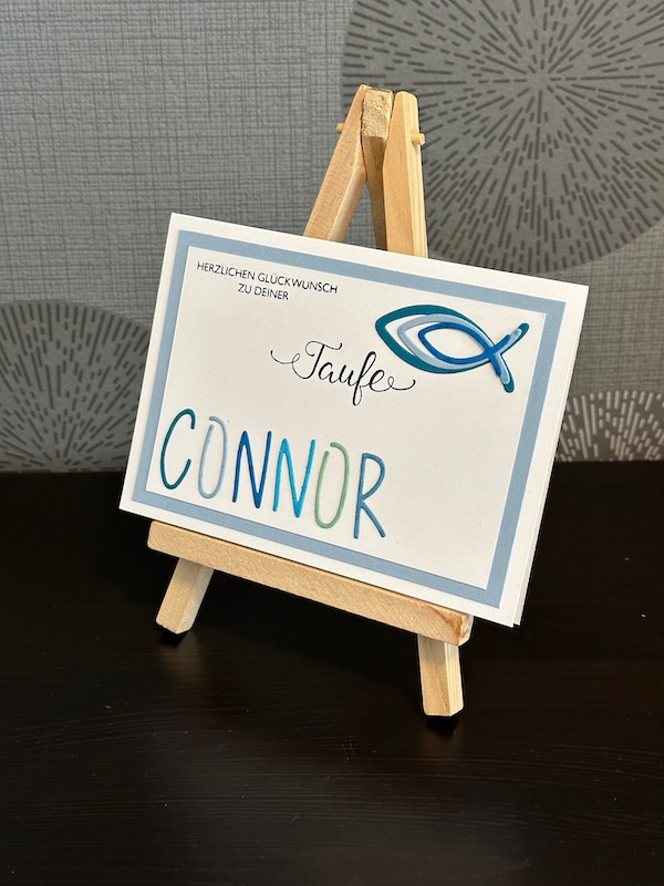 Glückwunschkarte zur Taufe von einem Jungen mit Fischen und seinem Namen in ausgestanzten Buchstaben.
