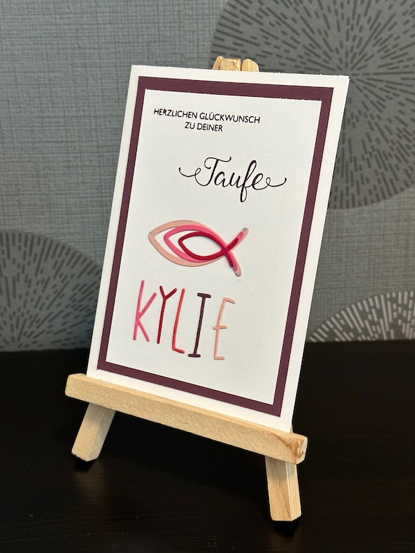 Glückwunschkarte zur Taufe von einem Mädchen mit Fischen und ihrem Namen in ausgestanzten Buchstaben.