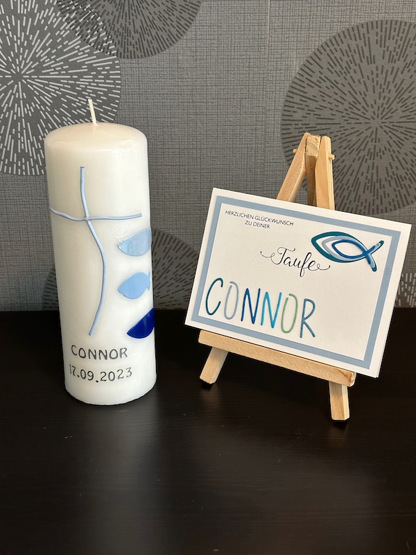 Glückwunschkarte zur Taufe mit Fischen und dem Namen in ausgestanzten Buchstaben. Passend dazu eine selbst gestaltete Taufkerze von Kerstins Kartenwerkstatt