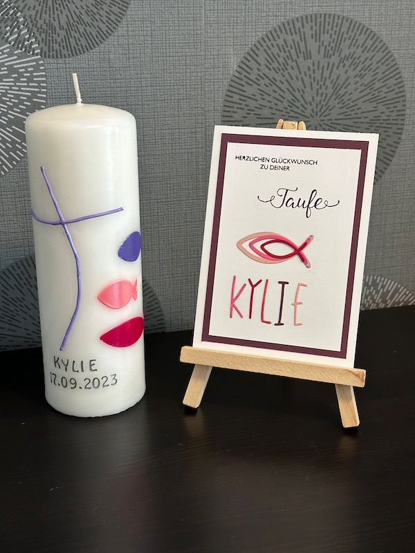Glückwunschkarte zur Taufe mit Fischen und dem Namen in ausgestanzten Buchstaben. Passend dazu eine selbst gestaltete Taufkerze von Kerstins Kartenwerkstatt