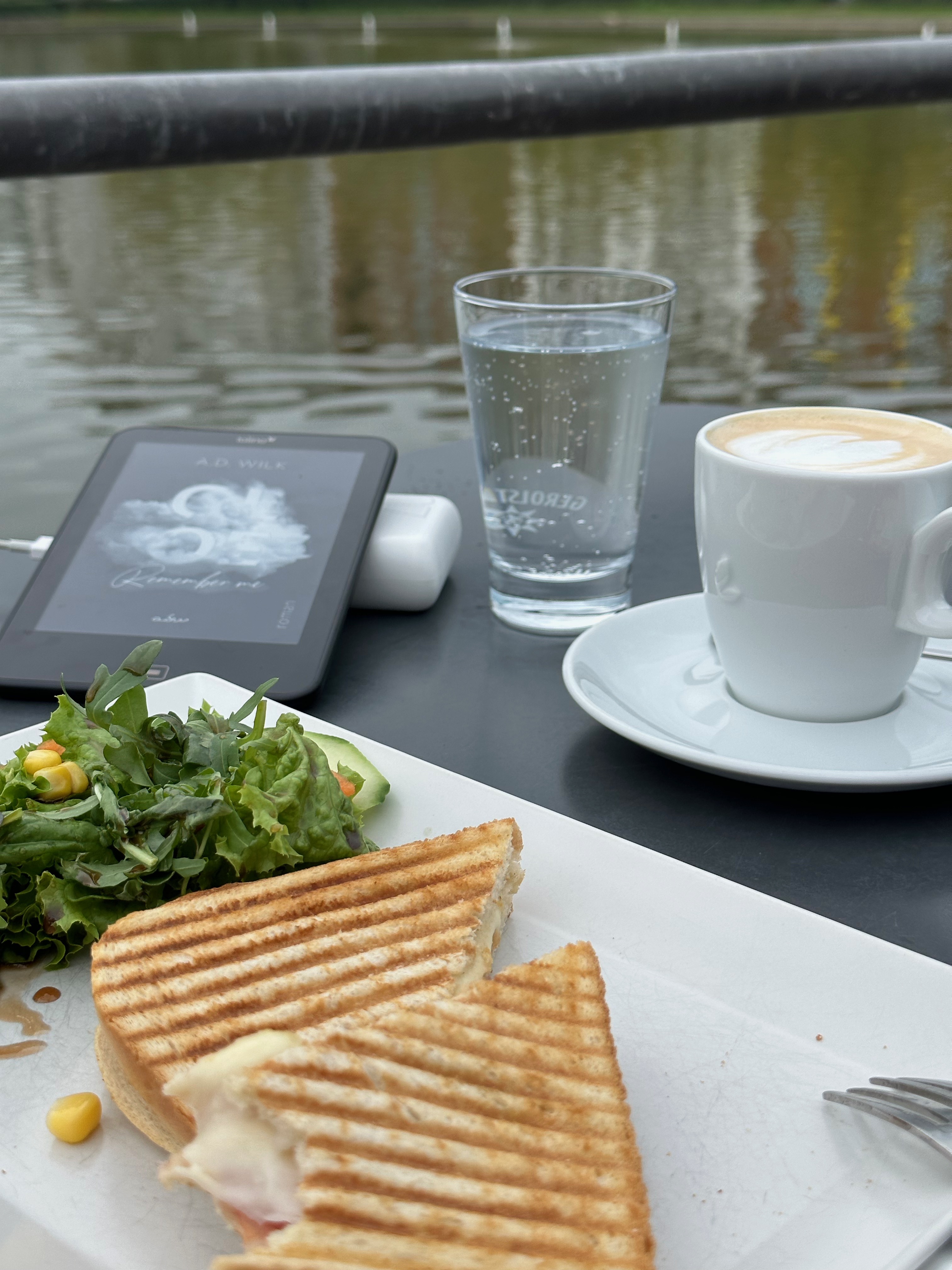 Kaffee und Toast auf der Terrasse vom Café am Engelsbecken in Berlin. Mit dabei das Ebook: CLOE. Remember me von A.D. Wilk.