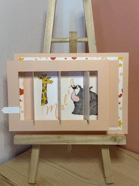 Sliderkarte zur Geburt eines Mädchens mit Babywiege. Zu sehen ist eine Karte in rosa, die man seitlich ziehen kann und dann das Bild von der Babywiege verschwindet und der Name des Kindes und Tiermotive dahinter hervorkommen. Gebastelt von Kerstins Kartenwerkstatt