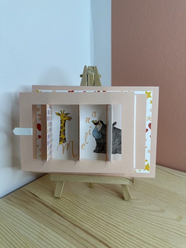 Sliderkarte zur Geburt eines Mädchens mit Babywiege. Zu sehen ist eine Karte in rosa, die man seitlich ziehen kann und dann das Bild von der Babywiege verschwindet und der Name des Kindes und Tiermotive dahinter hervorkommen. Gebastelt von Kerstins Kartenwerkstatt