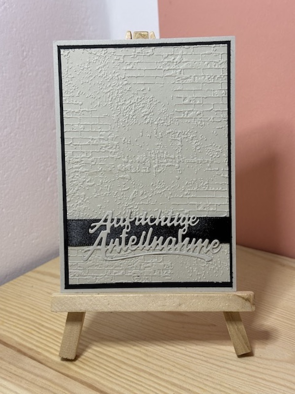 Trauerkarte in braun (Savanne) und schwarz mit ausgestanztem Schriftzug: Aufrichtiger Anteilnahme in braun(Savanne) auf einem schwarzen Streifen. Der Hintergrund ist geprägt.