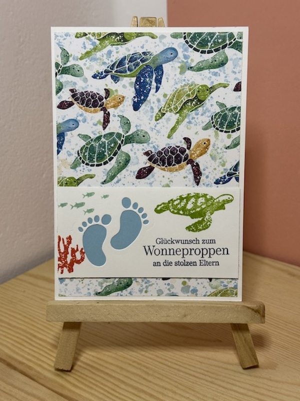 Zu sehen ist eine Glückwunschkarte zur Geburt. Auf der Babykarte ist der Spruch: "Glückwunsch zum Wonneproppen an die stolzen Eltern" gestempelt. Der Hintergrund ist durch das Designpapier mit Meerestieren einfach bunt und kann sowohl für Mädchen, als auch für Jungen verschenkt werden.