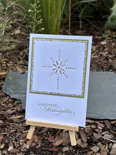 Zu sehen ist eine Weihnachtskarte gebastelt mit Material von Stampin Up. Ein weißes Quadrat ist sternförmig gelocht. Durch die einzelnen Löcher des Sterns funkelt das Gold vom Hintergrund hindurch. Darunter steht der Spruch "Gesegnete Weihnachten"