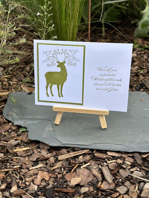 Zu sehen ist eine weiße Weihnachtskarte auf der in Olivgrün ein Hirsch mit verschnörkeltem Geweih gestempelt ist. Als Spruch steht auf der Karte: VOn Herzen zauberhafte Weihnachten und alle guten Wünsche fürs neue Jahr. Gebastelt wurde die Karte mit Material von Stampin Up