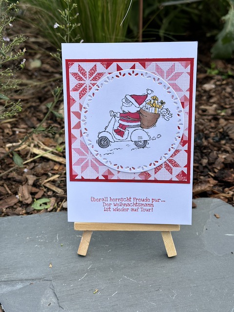 Zu sehen ist eine Weihnachtskarte. Auf dem runden Aufleger st der Weihnachtsmann auf dem Roller aus dem Stempelset von Stampin Up: "Heiter bis weihnachtlich" zu sehen. Dahinter ist befindet sich weihnachtliches Designpapier