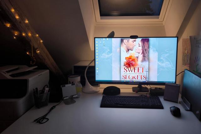 Zu sehen ist ein Foto vom Arbeitsplatz der Autorin Jes Schön. Auf dem Bildschirm sieht man das Cover vom Roman: Sweet Secrets