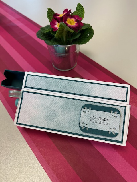 Zu sehen ist eine gebastelte Box mit zwei Fächern. Eins wird aufgeklappt in dem zweiten ist eine Schublade. Doppelte Box