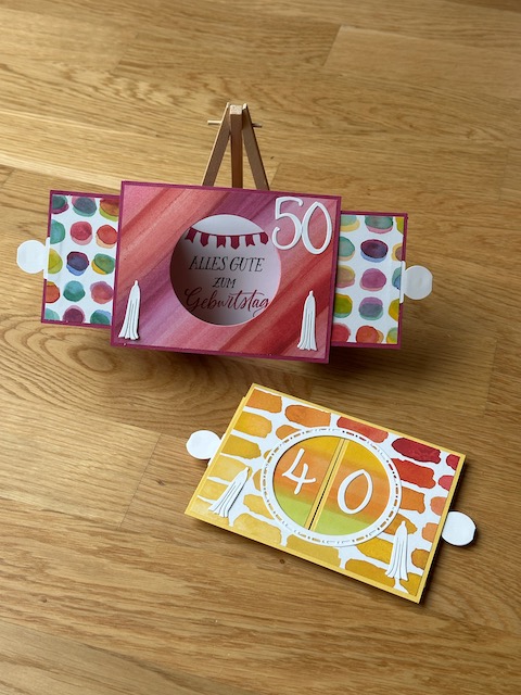Zu sehen ist eine Ziehkulissen Karte zum 40. bzw. 50. Geburtstag. Die Geburtstagskarte zeichnet sich dadurch aus, dass man an beiden Seiten ziehen kann und man dann durch den freien Kreis auf ein Bild dahinter Blicken kann. Ist die Karte auseinandergezogen, kann sie von alleine stehen. Farblich sind es gelb und rot Töne aus Material von Stampin Up gefertigt
