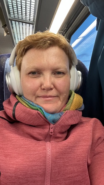 Kerstin im Zug auf der Rückfahrt mit Kopfhörer und kleinen Augen