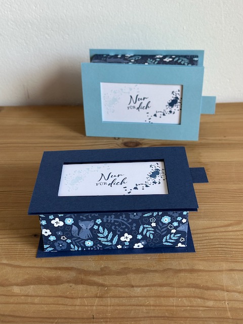 Zu sehen ist eine handgemachte Schachtel aus Papier. Der Deckel lässt sich durch Ziehen bzw. Schieben entfernen und gibt so den Spruch, der auf den Boden der Schachtel gestempelt ist frei. Die Box ist in Blau Weiß gehalten. Oben drauf steht ganz schlicht und einfach "für dich"