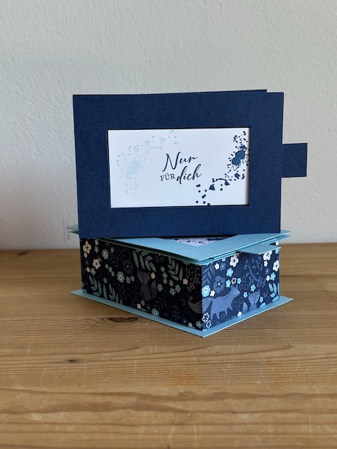 Zu sehen ist eine handgemachte Schachtel aus Papier. Der Deckel lässt sich durch Ziehen bzw. Schieben entfernen und gibt so den Spruch, der auf den Boden der Schachtel gestempelt ist frei. Die Box ist in Blau Weiß gehalten. Oben drauf steht ganz schlicht und einfach "für dich"