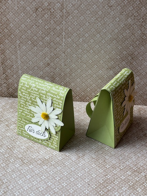 Handgemachter kleiner Rucksack, der an einen Schulranzen erinnert. Die Tasche ist mit einem Designpapier mit Schriftzügen verziert und als Accessoirs sind Gänseblümchen auf der Klappe drapiert. Ergänzt wird das ganze mit dem Spruch: Für dich und so ist dieser kleine Schulranzen nicht nur ein Geschenk zur Einschulung, sondern auch ein ganz persönliches Geschenk zu jeglichem Anlass