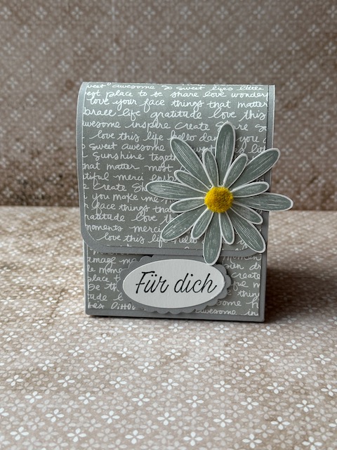 Handgemachter kleiner Rucksack, der an einen Schulranzen erinnert. Die Tasche ist mit einem Designpapier mit Schriftzügen verziert und als Accessoirs sind Gänseblümchen auf der Klappe drapiert. Ergänzt wird das ganze mit dem Spruch: Für dich und so ist dieser kleine Schulranzen nicht nur ein Geschenk zur Einschulung, sondern auch ein ganz persönliches Geschenk zu jeglichem Anlass