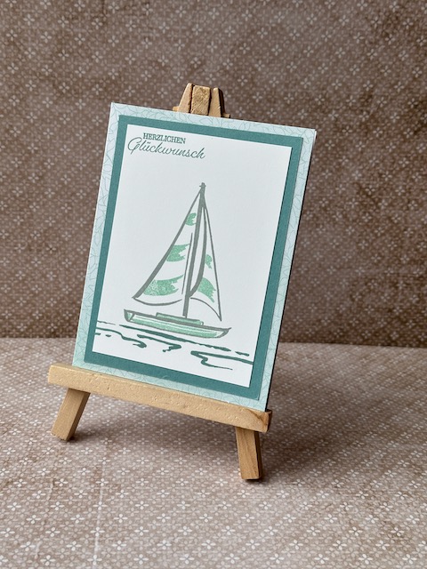 Zu sehen ist eine Geburtstagskarte in grün Tönen mit einem gestempelten Segelboot und Herzlichen Glückwunsch drauf.