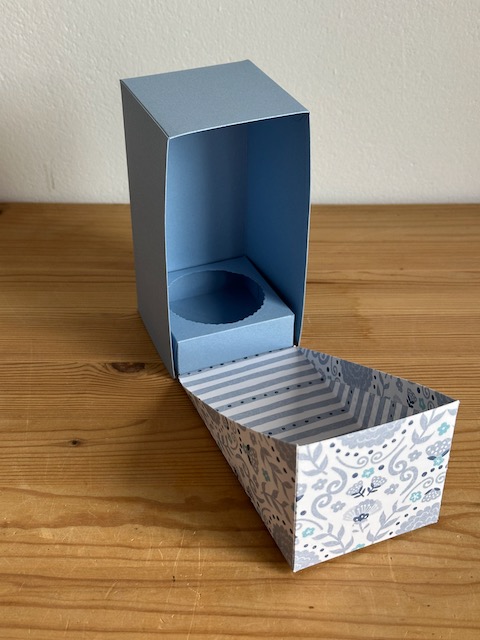 Zu sehen ist eine selbstgemachte Verpackung, die PLatz bietet für eine Prosecco Dose. Die Grundform ist ein Quader, wobei der Deckel Diagonal über die Schachtel geklappt wird und so raffiniert aussieht. 