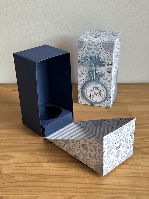 Zu sehen ist eine selbstgemachte Verpackung, die PLatz bietet für eine Prosecco Dose. Die Grundform ist ein Quader, wobei der Deckel Diagonal über die Schachtel geklappt wird und so raffiniert aussieht. 