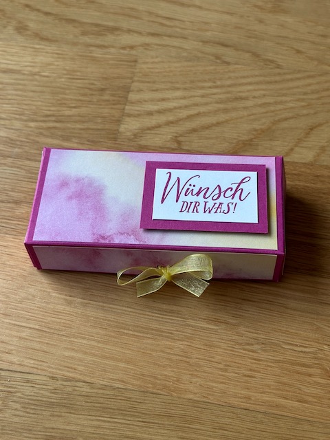 Zu sehen ist eine selbstgebastelte Box, die man aufklappen kann. Sichtbar wird ein Schlitz, in den eine Gutscheinkarte gesteckt werden kann. In der Box ist außerdem noch PLatz für etwas süßes zum Beispiel drei bis vier kleine Schokoladenkugeln