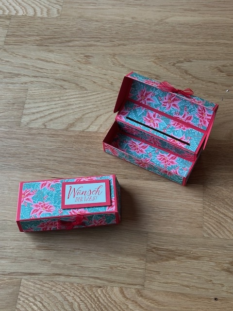 Zu sehen ist eine selbstgebastelte Box, die man aufklappen kann. Sichtbar wird ein Schlitz, in den eine Gutscheinkarte gesteckt werden kann. In der Box ist außerdem noch PLatz für etwas süßes zum Beispiel drei bis vier kleine Schokoladenkugeln