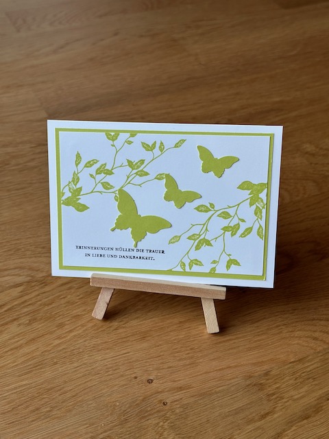 Zu sehen ist eine selbstgebastelte Trauerkarte. Allerdings nicht in klassischem schwarz weiß. Auf der weißen Grundkarte klebt ein grün Layer und darauf ein weitere in weiß. Dieser ist mit grün bestempelt. Darüber wurde ein grüner Schmetterling geklebt. Einzig die Beileidswünsche sind in schwarz gestempelt.
