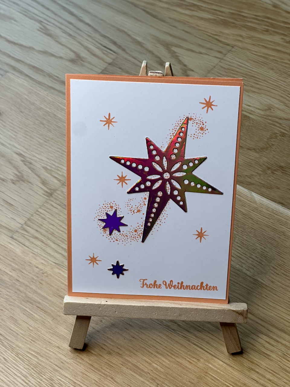 Selbstgebastelte Weihnachtskarten mit metallischen Akzenten auf Papier. In blau, orange und rot. Jeweils mit Schneemann oder Stern und einem besonderen Glitzern, wenn man die Karte im Licht bewegt.