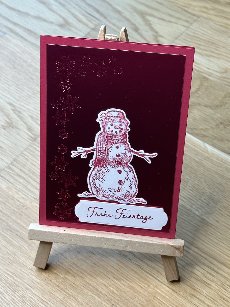 Selbstgebastelte Weihnachtskarten mit metallischen Akzenten auf Papier. In blau, orange und rot. Jeweils mit Schneemann oder Stern und einem besonderen Glitzern, wenn man die Karte im Licht bewegt.